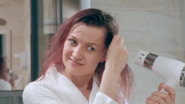 Jonge mooie vrouw in de badkamer droogt haar haar met een haardroger. — Stockvideo