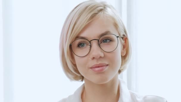 白い背景にメガネで短い髪を持つ若い美しい女性ブロンド。賢く、エレガントな、勝利に喜び、慎重に見える. — ストック動画