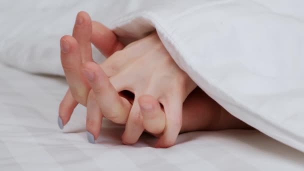 Le mani della coppia, uomini e donne sporgono da sotto la coperta. Le dita sono tessute. Dolcezza e amore . — Video Stock