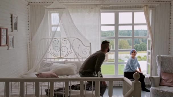 Junges schönes Paar in warmen Pullovern in einem Landhaus vor dem Fenster. Umarmungen und familiäre Beziehungen. — Stockvideo