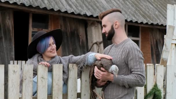 Junge schöne Mann und Frau, Ehepaar, in einem Dorf auf einem Bauernhof, mit einem Truthahn in den Händen. bäuerliche Familienbetriebe. — Stockvideo