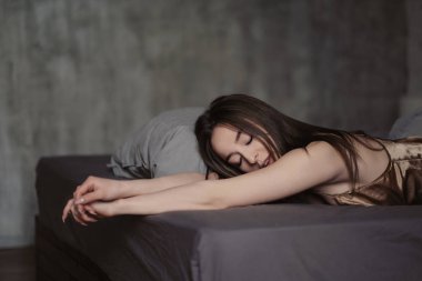 Güzel seksi esmer kadın yatakta yatıyor. Yüz yakın çekim, güzel kahverengi gözler, dudaklar ve gülümseme.