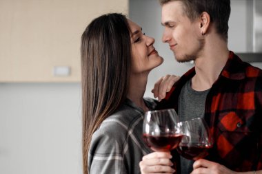 Mutfakta ekose gömlek güzel genç çift yiyecek hazırlanıyor ve gözlük kırmızı şarap içme.