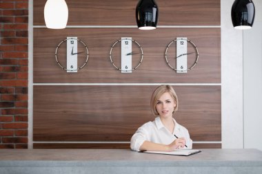 Beyaz gömlek kısa saçlı genç güzel sarışın kız. Otelin resepsiyonundaki resepsiyonist.