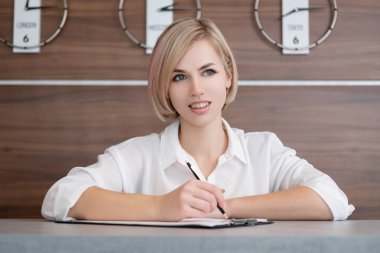 Beyaz gömlek kısa saçlı genç güzel sarışın kız. Otelin resepsiyonundaki resepsiyonist.