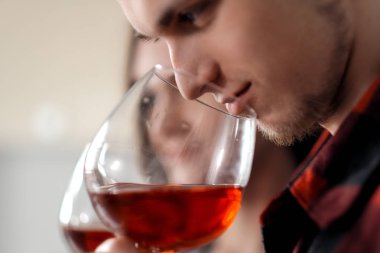 Mutfakta ekose gömlek güzel genç çift yiyecek hazırlanıyor ve gözlük kırmızı şarap içme.
