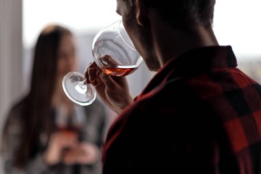 Çok katlı bir binanın balkonunda ekose gömlek genç güzel çift. İçve tadına şarap, gülmek ve kucaklamak.