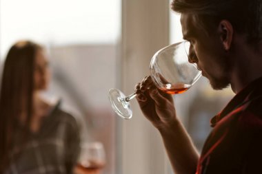 Çok katlı bir binanın balkonunda ekose gömlek genç güzel çift. İçve tadına şarap, gülmek ve kucaklamak.