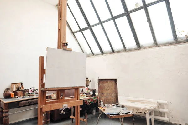 Estúdio de arte brilhante com uma grande janela. Bagaços e telas . — Fotografia de Stock