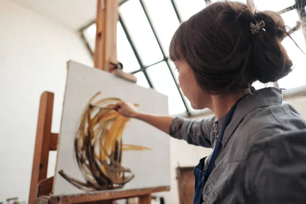 Joven mujer hermosa pintor entre caballetes y lienzos en un estudio brillante . — Foto de Stock