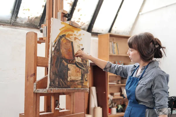 Mujer artista pinta un cuadro sobre lienzo. Luminoso estudio de arte con una gran ventana. caballetes y lienzos . — Foto de Stock