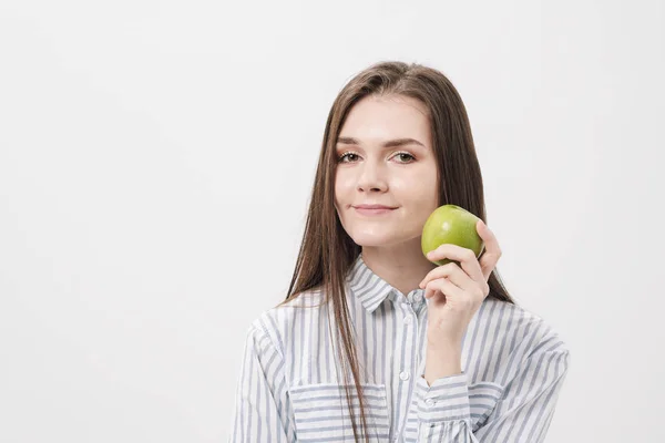 Giovane bella ragazza bruna su uno sfondo bianco con una mela verde fresca . — Foto Stock