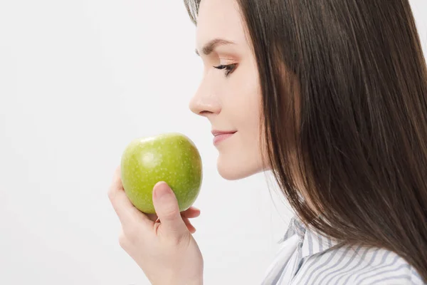 Молодая красивая брюнетка девушка на белом фоне, держа свежее зеленое яблоко . — стоковое фото