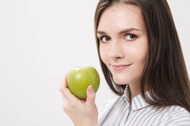 Taze yeşil elma tutan beyaz bir arka plan genç güzel esmer kız.