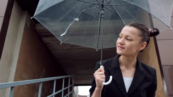 검은 색 재킷과 청바지에 젊은 매력적인 여자는 건물의 배경에 야외 포즈. — 비디오