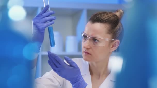 Жінка-медик працює в лабораторії. Спеціаліст проводить експерименти, розробляє аукцин з вірусу. Коронавірус covid-19. — стокове відео