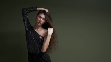 Genç ve şehvetli bir kadın model yeşil arka planda poz veriyor. Stüdyoda moda çekimi..