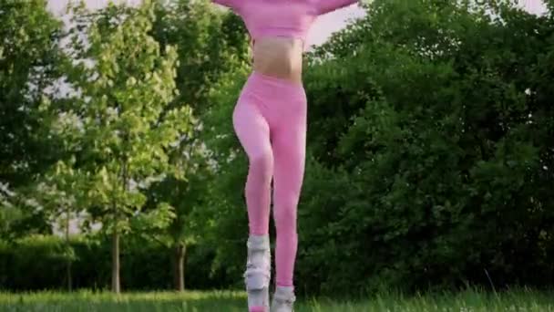 En ung smal vacker kvinna med dreadlocks i sportkläder tåg i parken utomhus. Kangoo hoppar träning. — Stockvideo