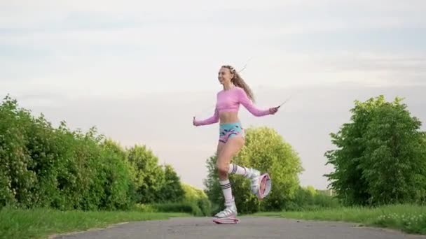 Una giovane donna snella e bella con i dreadlock nei treni di abbigliamento sportivo nel parco all'aperto. Kangoo salta l'allenamento. — Video Stock