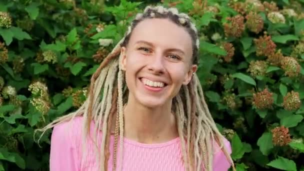 A young beautiful woman in a pink T-shirt with white dreadlocks outdoors. — Stock Video