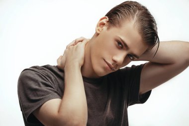 T-shirt yakışıklı rahat adam. Genç bir baştan çıkarıcı adam, kafasını gri studio arka plan eller ile kameraya bakarak portresi. Beden dili. Kişi, reklam ve reklam kavramı.