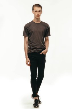 Kendinden emin ve neşeli izole tam uzunlukta portre yakışıklı beyaz erkek. Tam kamera ayakta beyaz arka plan bakarak vuruş. Rahat t-shirt giymiş. İnsanlar, reklam ve