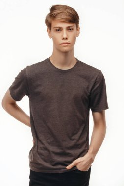 İzole stüdyo portre yakışıklı beyaz erkek modeli ile şık saçlı, kahverengi gözlü, giyinmiş kameraya bakarak ve kapalı karşı studio beyaz arka plan ayakta rahat t-shirt içinde. Aktör veya