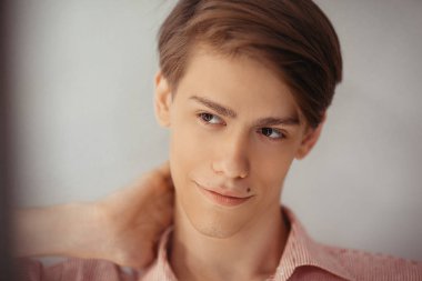 Kahverengi gözleri ile erkeksi çekici Avrupa Genç adam yakın yukarı portre, gülümseyen. El bir boyun, çizgili gömlek kapalı ampul ile boş arka plana karşı. İnsanlar, reklamlar ve