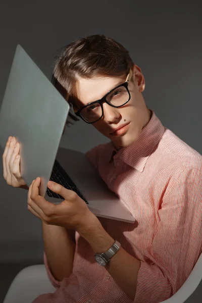 IT computer nerd. Creative teen millenial portrait indoors. Funny young man with happy face expression in glasses hug laptop against dark background. Internet, video game addiction concept — Stock Photo, Image