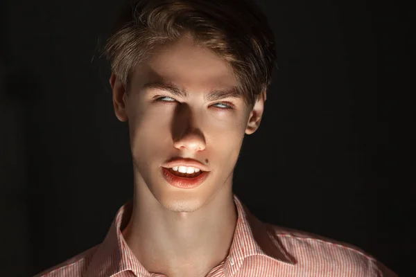 Close-up portrait of attractive kind young man rolled his eyes in stripped shirt. Isolated on black background and looking at camera. Funny or fear concept. — Stock Photo, Image