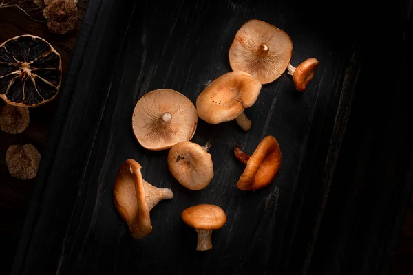 Agrupar el hongo crudo, con limón seco y semillas secas, sobre fondo de madera negra. Vista superior, espacio para texto —  Fotos de Stock