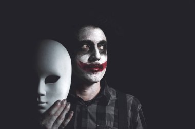 ürpertici palyaço holding beyaz maske