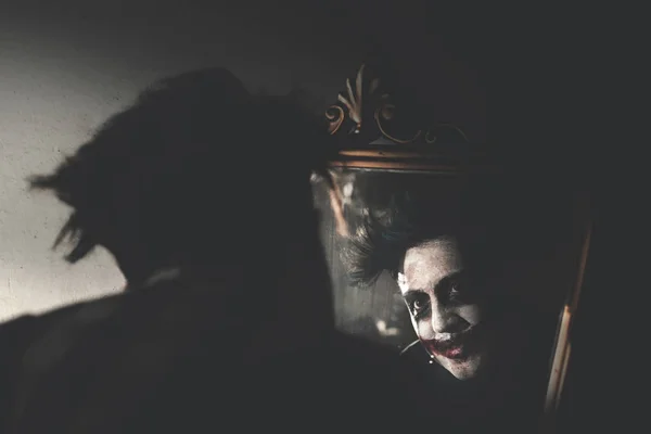 creepy clown smiling in front of mirror