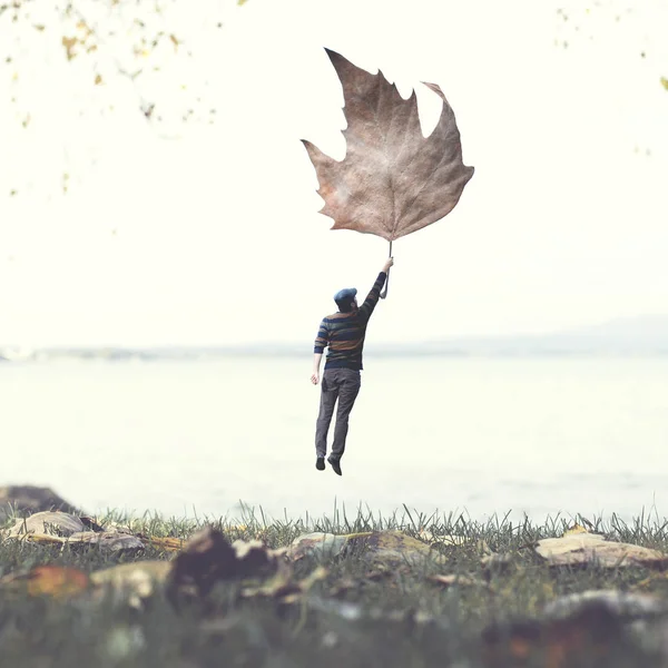 man flying with a leaf , autumnal surreal concept