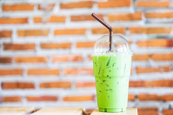 冰绿茶拿铁与牛奶在塑料杯在咖啡厅的木桌上 — 图库照片