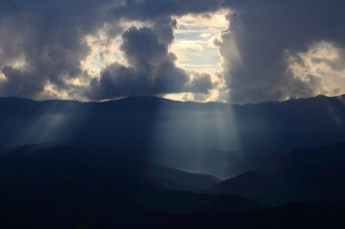 Bulutların arasından geçen ve sıradağları üzerinde parlayan dramatik Tanrı ışık. sıcak ışık duş. Tanrı umut ve kavram hayal