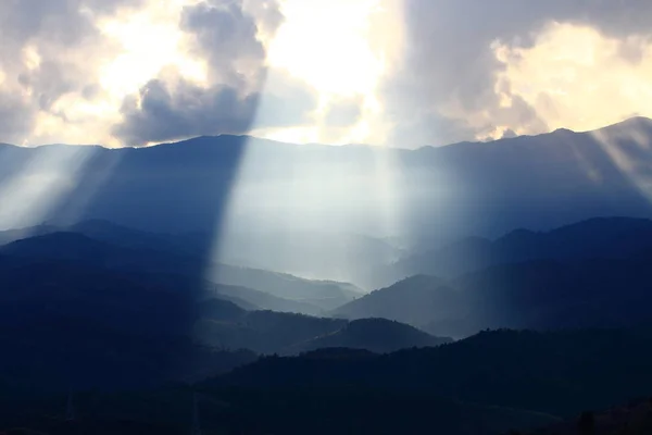 stock image Dramatic god lights passing through clouds and shining on mountain ranges. warm light shower. God hope and dream concept