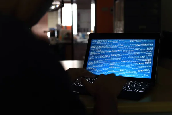 Karanlık bir odada bilgisayarda yazarak bilgisayar Hacker siluet. Mavi ikili kod teknolojisi üzerine çalışıyor. ikili veri, bilgisayar programlama ve ağ güvenlik kavramları.