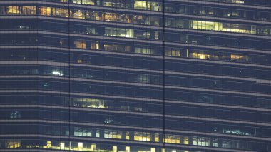 çok katlı ofis işçi fazla mesai ile gece. geç gece ofisinde. aydınlatma ve çalışan insanlar içinde. Gece geç saatlerde mesai aglasses çelik ve alüminyum kaplı modern ofis