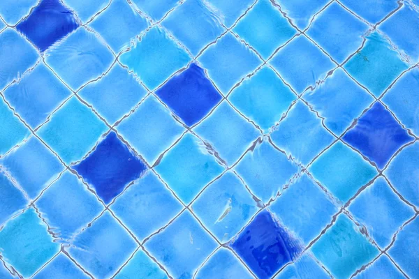 swimming pool ceramic tiles covered in clear water. light blue tiles dotted with deep blue tiles in a regular pattern design. recreation pool design.