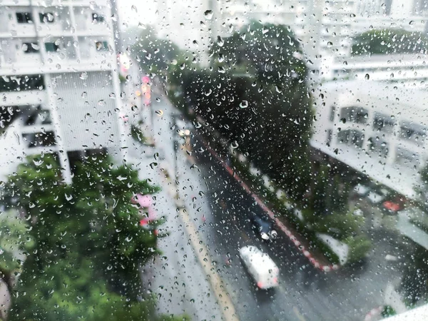 raining on the street, aerial view. water drop caught on glass apartment window.  looking down on road during storm. wet street and careful driving concept.