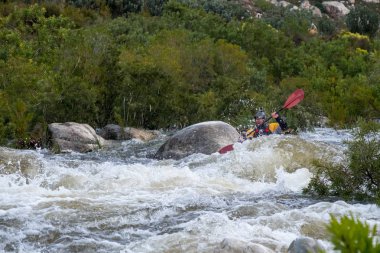 Bazı beyaz su rapids Du Toits Kloof yakınındaki Cape Town Güney Afrika nehir üzerinde aracılığıyla doldurma turuncu bir kayık içinde bir kanocu görüntüsünü