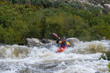Bazı beyaz su rapids Du Toits Kloof yakınındaki Cape Town Güney Afrika nehir üzerinde aracılığıyla doldurma turuncu bir kayık içinde bir kanocu görüntüsünü