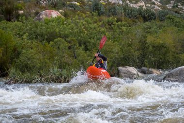 Bazı beyaz su rapids Du Toits Kloof yakınındaki Cape Town Güney Afrika nehir üzerinde aracılığıyla doldurma turuncu bir kayık içinde bir kanocu görüntüsünü