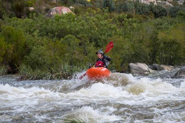 Bazı beyaz su rapids Du Toits Kloof yakınındaki Cape Town Güney Afrika nehir üzerinde aracılığıyla doldurma turuncu bir kayık içinde bir kanocu görüntüsünü