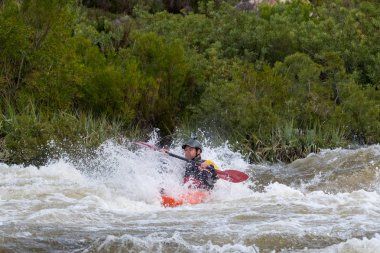 Bazı beyaz su rapids Du Toits Kloof yakınındaki Cape Town Güney Afrika nehir üzerinde aracılığıyla doldurma turuncu bir kayık içinde bir kanocu görüntüsünü