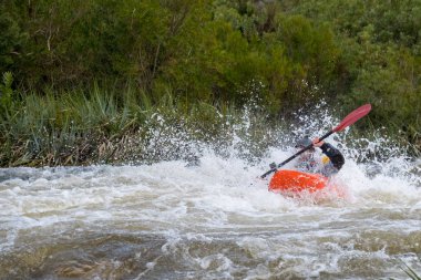 Bazı beyaz su rapids Du Toits Kloof yakınındaki Cape Town Güney Afrika nehir üzerinde aracılığıyla doldurma turuncu bir kayık içinde bir kanocu görüntüsünü