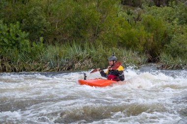 Bazı beyaz su rapids Du Toits Kloof yakınındaki Cape Town Güney Afrika nehir üzerinde aracılığıyla doldurma turuncu bir kayık içinde bir kanocu görüntüsünü