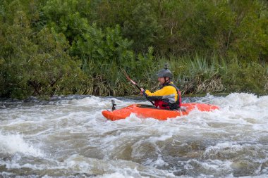 Bazı beyaz su rapids Du Toits Kloof yakınındaki Cape Town Güney Afrika nehir üzerinde aracılığıyla doldurma turuncu bir kayık içinde bir kanocu görüntüsünü