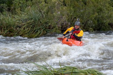 Bazı beyaz su rapids Du Toits Kloof yakınındaki Cape Town Güney Afrika nehir üzerinde aracılığıyla doldurma turuncu bir kayık içinde bir kanocu görüntüsünü